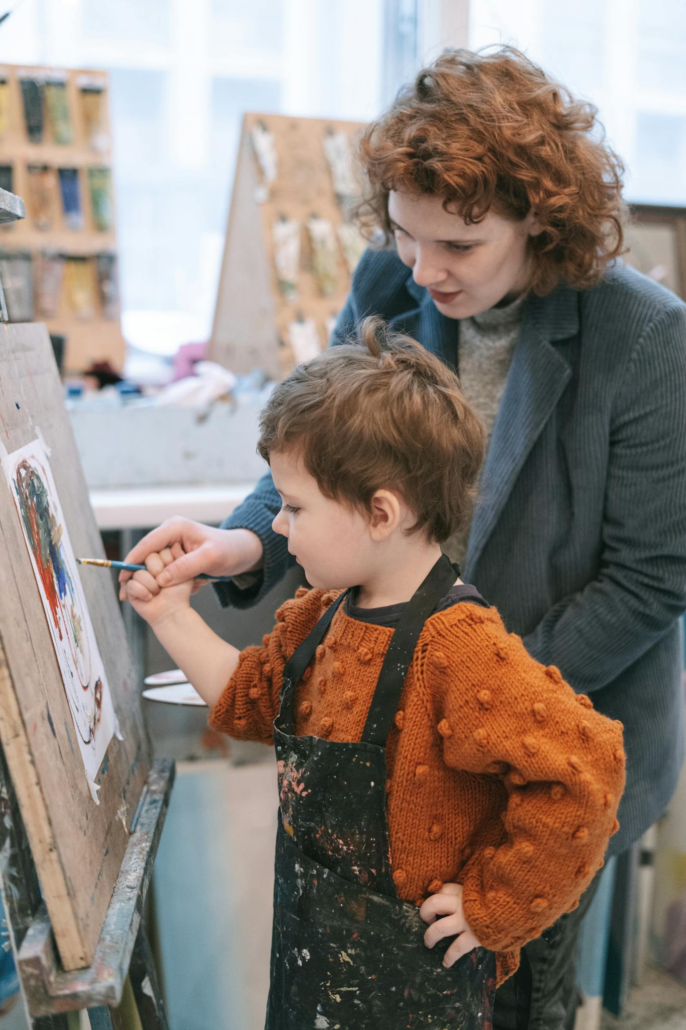 A mother helps her child paint in an art studio, fostering creativity and learning.