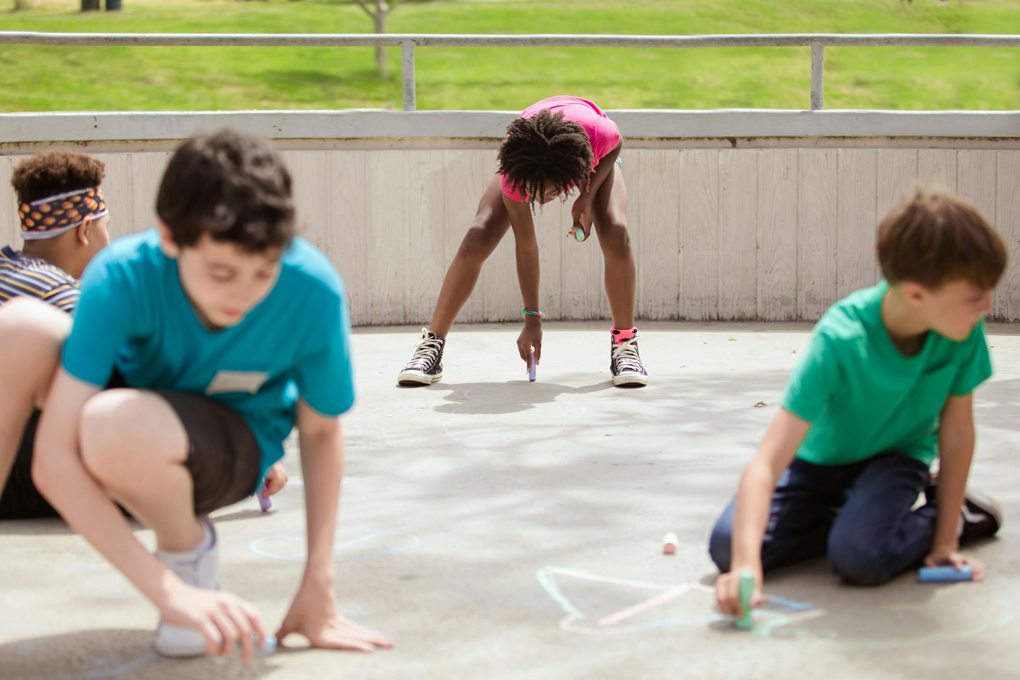 Children creatively drawing with chalk on pavement, showcasing diversity and teamwork.